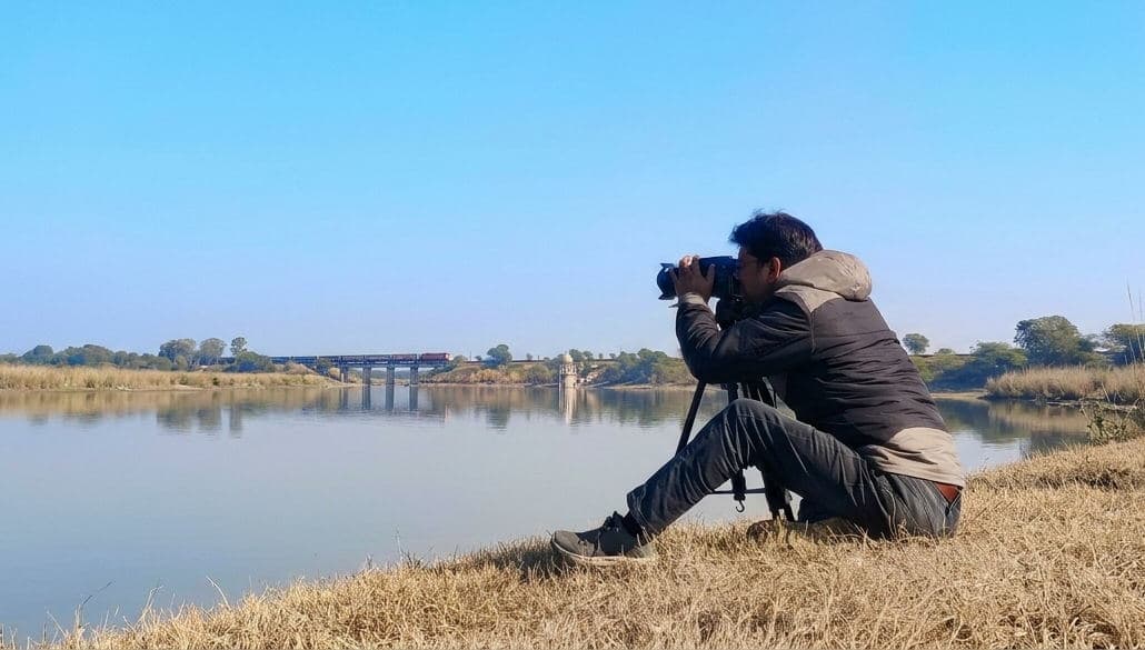 Vijay Kumawat using a telephoto camera beside a lake in Ranthambore